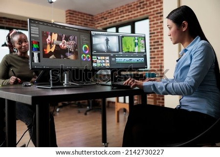 Videography expert in post production house editing footage frames and improving visual quality using specialized software. Video editor in creative agency room sitting at multi monitor workstation.