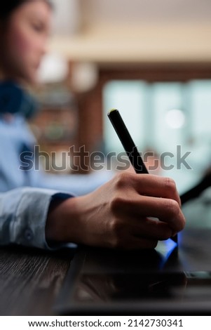 Close up of digital photo editor sitting at desk with multiple displays while using editing software to retouch images. Creative graphic designer using stylus pen and graphic tablet to edit photos.