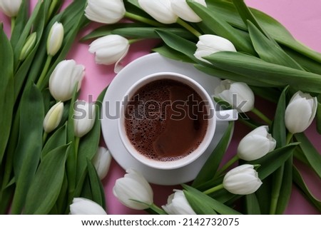 Cup of coffee among arranged white tulips