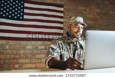 Patriotic young soldier video chatting with his family from the military base. American serviceman communicating with his loved ones while serving his country in the army. Royalty-Free Stock Photo #2142733487