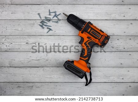 Cordless hand drill for used as normal drill, impact drill and screwdriver, power tool. Cordless impact screwdriver and self-tapping screws for wood on wooden background.  Royalty-Free Stock Photo #2142738713