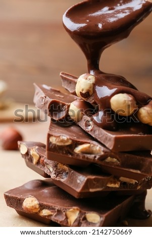 Pouring of liquid chocolate onto pieces with nuts on table, closeup Royalty-Free Stock Photo #2142750669