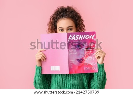 Young African-American woman in green sweater reading magazine on pink background Royalty-Free Stock Photo #2142750739