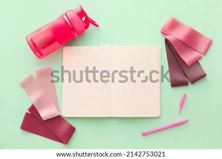 Stylish sport equipment and blank notebook on green background