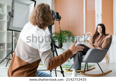 Photographer taking picture of female model in modern studio