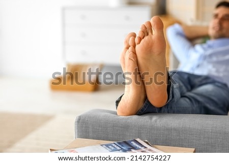 Bare feet of young man relaxing on sofa at home, closeup Royalty-Free Stock Photo #2142754227