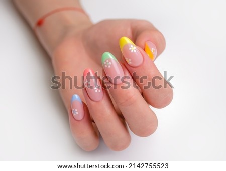 Hands of a young woman with a manicure. The nails are covered with gel polish with colored French and flowers Royalty-Free Stock Photo #2142755523
