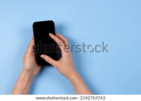 Female hand touching smartphone display screen, using app, browsing internet, shopping online, light blue background with copy space for text