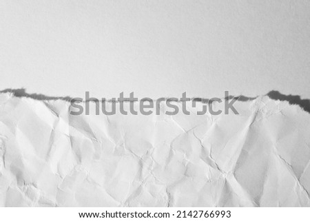 Torn, crumpled sheet of paper on a white background. Top view, macro photo.