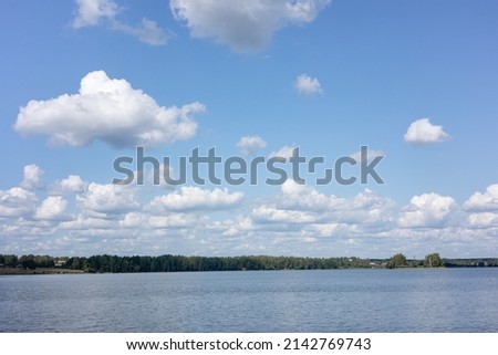 Summer countryside landscape with blue sky and calm water of river.