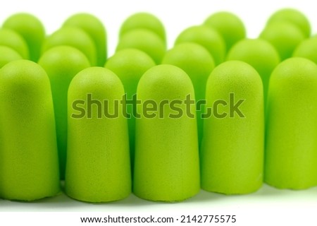 Three rows of soft light green foam earplugs on a white background, close-up. Soft foam ear plugs.The concept of getting rid of noise in a noisy place, hearing protection.High quality photo