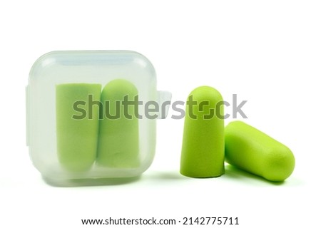 Soft light green foam earplugs in a plastic container and pair of earplugs on a white background.Close-up.The concept of getting rid of noise in a noisy place, hearing protection.High quality photo