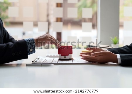Real estate agent sales manager giving house model to customer after signing rental lease contract of sale purchase agreement, concerning mortgage loan offer for and house insurance.