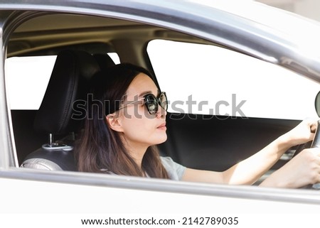 Happy asian woman driving a eco hybrid car.Happy woman is driving a car service.Portrait female driver steering car with safety belt.Electric vehicle.used car rental.Learning to drive.vacation travel. Royalty-Free Stock Photo #2142789035