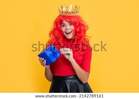 happy child in crown with present on yellow background. wow