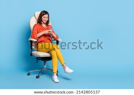Full size photo of young lovely lady sit stool use cellphone type comment share app download isolated over blue color background
