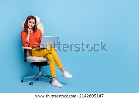 Portrait of attractive minded girl sitting in armchair using laptop deciding copy space isolated over bright blue color background Royalty-Free Stock Photo #2142805147