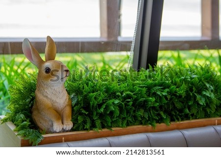 Plaster rabbit sculpture in the green garden for interior decoration, select focus