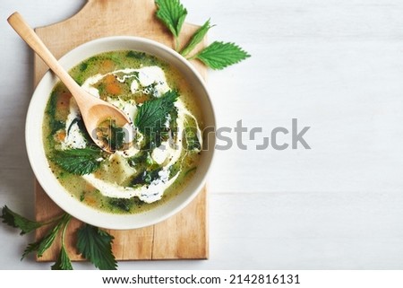 Vegan nettle soup on rustic wooden table. Healthy vegan nettle soup served in bowl on rustic wooden table. Royalty-Free Stock Photo #2142816131