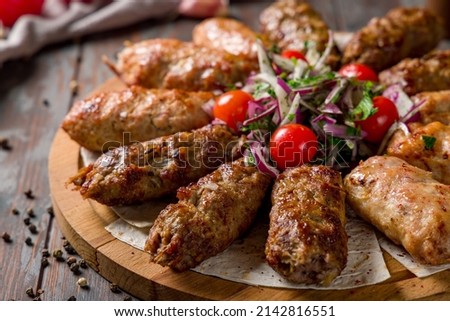 Assorted lula kebabs on board with red onion, Lamb Lula kebab, beef lula kebab, chicken lula kebab on the board on old wooden table macro close up Royalty-Free Stock Photo #2142816551