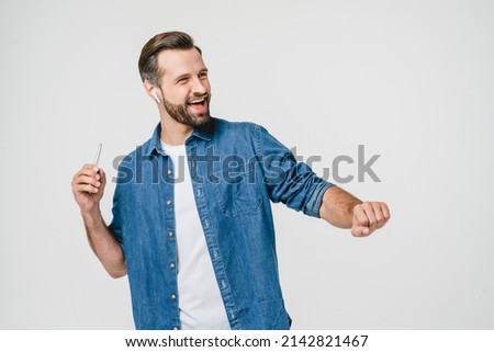 Happy active caucasian young man student music lover listening to the radio podcast playlist, dancing in headphones earphones isolated in white background
