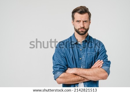 Offended sad angry caucasian young man with arms crossed blowing his lips looking at camera isolated in white background. Conflict anger concept Royalty-Free Stock Photo #2142821513