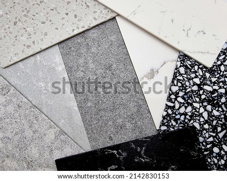 close up view of different quartz samples textures for kitchen counter top. various colors and textures of artificial stones including marble, pebbles, grainy surface (focused at center of image). Royalty-Free Stock Photo #2142830153