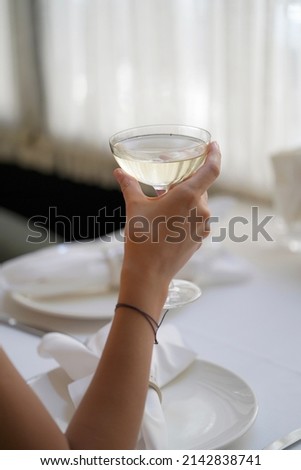 Woman hand holding glass with martini cocktail, close-up. Woman drink fresh cocktail at restaurant