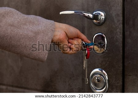 A woman opens the front door with keys.Using keys to open and close the door lock.The landlord opens the door from a new house. Royalty-Free Stock Photo #2142843777