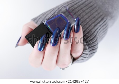 Woman's beautiful hand with long nails and blue and green nail polish