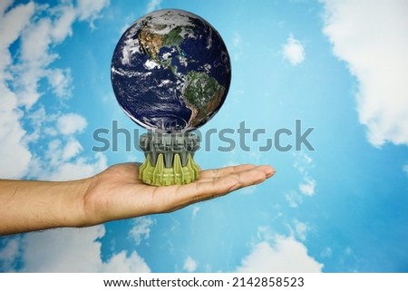 human hand holding the world earth above blue natural background. Safe world concept. Elements of this image furnished by NASA