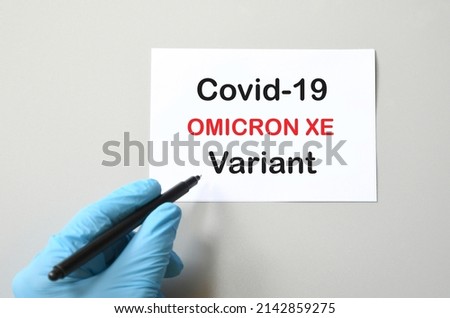 Covid-19 new Omicron XE Hand of the doctor in blue glove with marker and writing "Covid-19 Omicron XE" on white sheet. Concept for the new Covid 19 Omicron variant Royalty-Free Stock Photo #2142859275