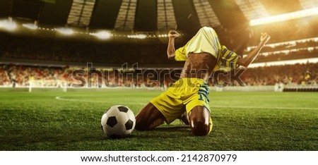Winner emotions of professional football player in action at the stadium with flashlights winning goal, wide angle. Concept of sport, competition, movement, overcoming. Local presence effect.
