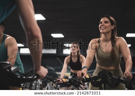 people on bikes in spinning class in modern gym, exercising on stationary bike. group of athletes training on exercise bike Royalty-Free Stock Photo #2142871011