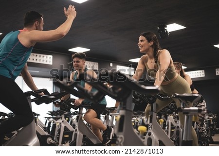 people on bikes in spinning class in modern gym, exercising on stationary bike. group of athletes training on exercise bike Royalty-Free Stock Photo #2142871013