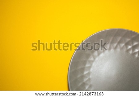 Gray plate for food on yellow background. Trending colors of 2021. Creative copy space