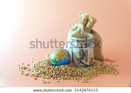 A sack of wheat, spilled, next to a globe, globe and US banknotes. Concept - world food crisis, export, import. The issue of harvest in different countries of the world, the impact of sanctions. Royalty-Free Stock Photo #2142876153