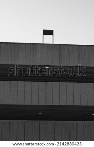 A sign standing on top of the local concrete parking garage in a minimalist view in black and white.