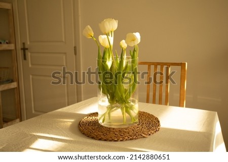 Spring flowers - white tulips in glass vase on wooden table