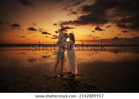 A Family on the beach concept, Caucasian family playing and carrying his daughter on the tropical beach in sunset.