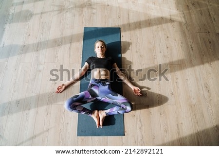 Supta Baddha Konasana pose of the resting goddess, asana butterfly lying on the floor, relaxation of the spine, rest of the muscles of the body, the girl practices recumbent yoga in the classroom Royalty-Free Stock Photo #2142892121