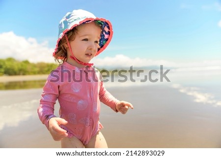 A little adorable girl 2 years joyfully on the beach in sunset on holiday