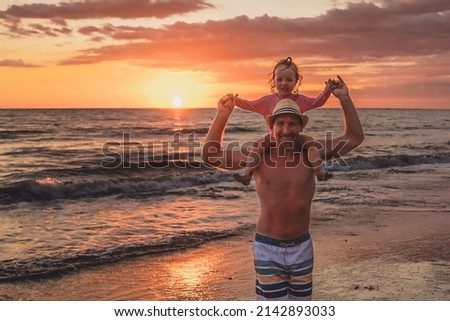 A happy family at the beach a father and baby daughter having fun at sunset