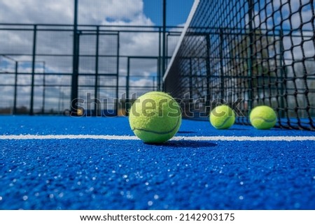 selective focus, four paddle tennis balls on a blue paddle tennis court close to the net, racket sports concept Royalty-Free Stock Photo #2142903175