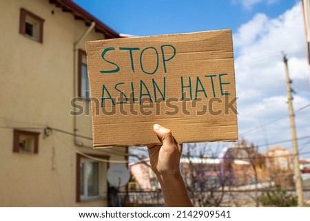 Hand holding stop asian hate placard. Woman protesting against to racism.