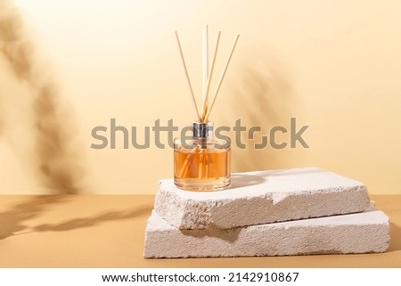 reed diffuser bottle on the podium. Incense sticks for the home with a floral scent with hard shadows. The concept of eco-friendly fragrance for the home Royalty-Free Stock Photo #2142910867