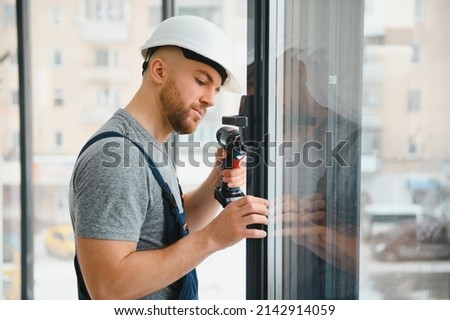 Construction worker using drill while installing window indoors Royalty-Free Stock Photo #2142914059