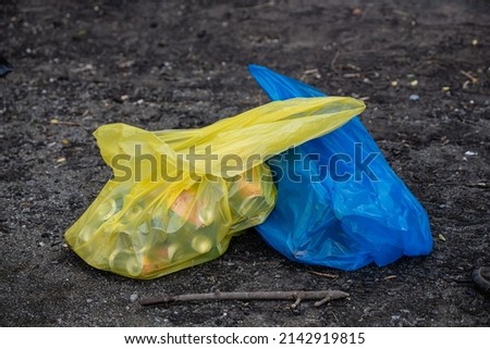 two blue-yellow bags with metal cans. garbage in nature