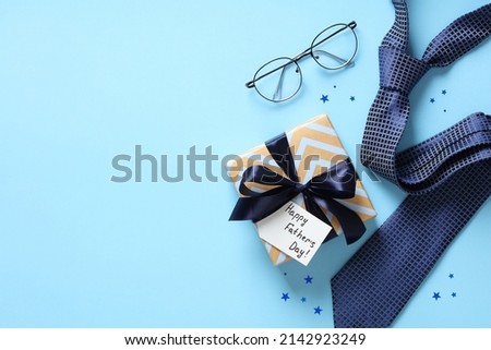 Happy Fathers Day concept. Flat lay composition with vintage gift box, eyeglasses, necktie on blue background. Royalty-Free Stock Photo #2142923249