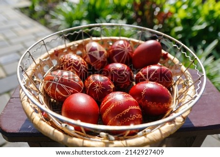 Defocus Closeup of basket of colored red eggs, Easter holiday concept. Modern painted easter eggs. Nature background, garden. Collection of pysanka or krashanka. Out of focus. 
